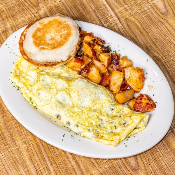 A breakfast plate with a folded omelet, crispy home fries, and a toasted English muffin.