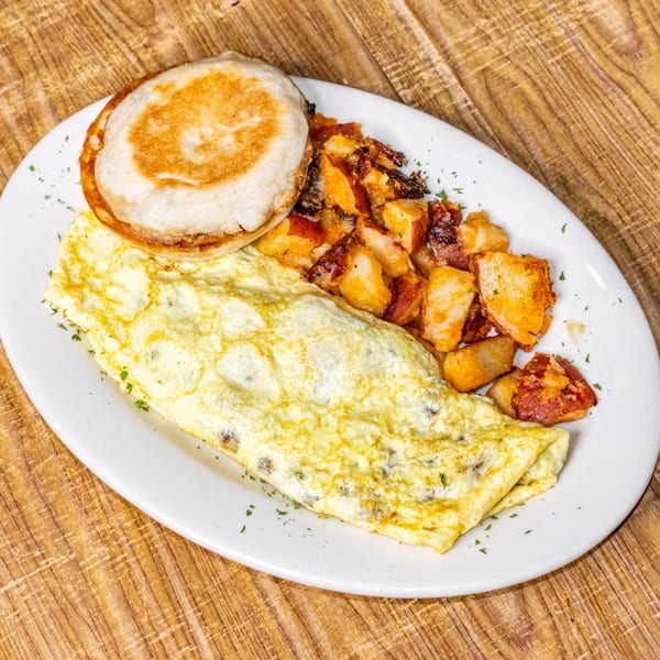 Breakfast plate with a golden-brown omelet, crispy home fries, and a toasted English muffin.